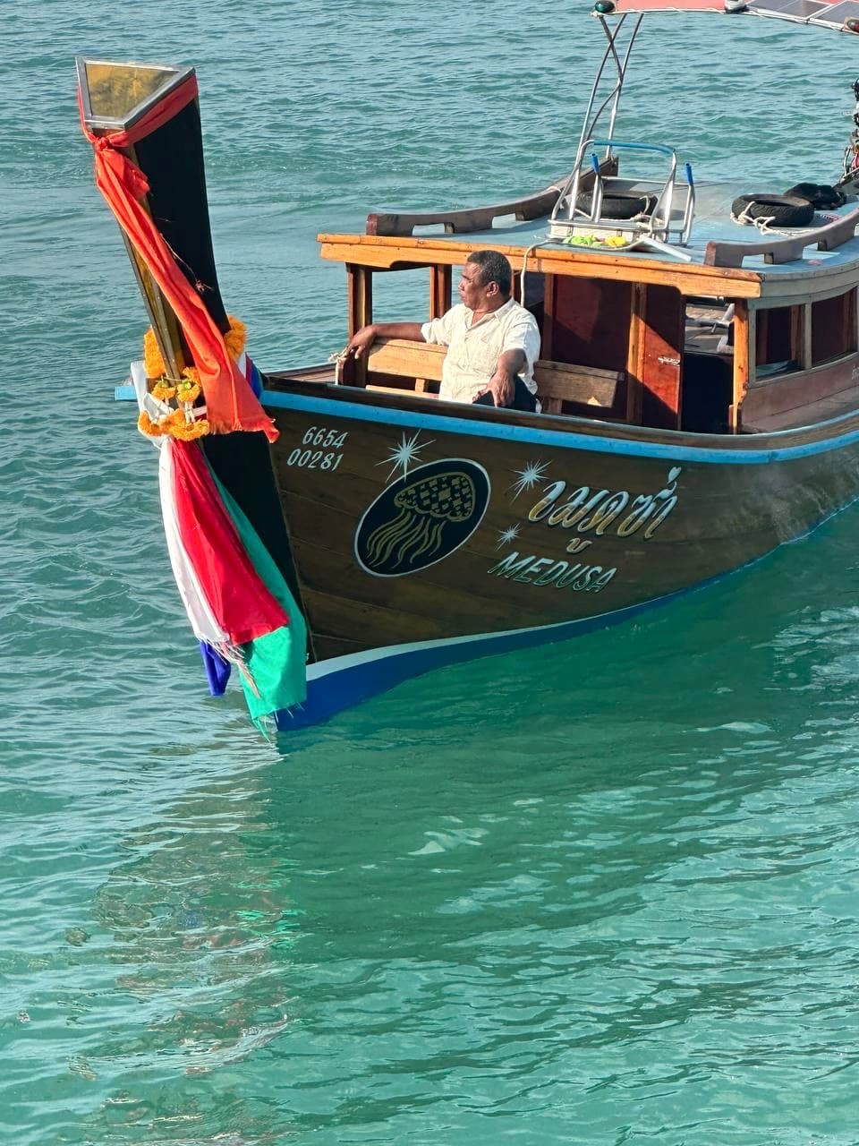 Detailed exterior of a wooden longtail boat in clear sea water