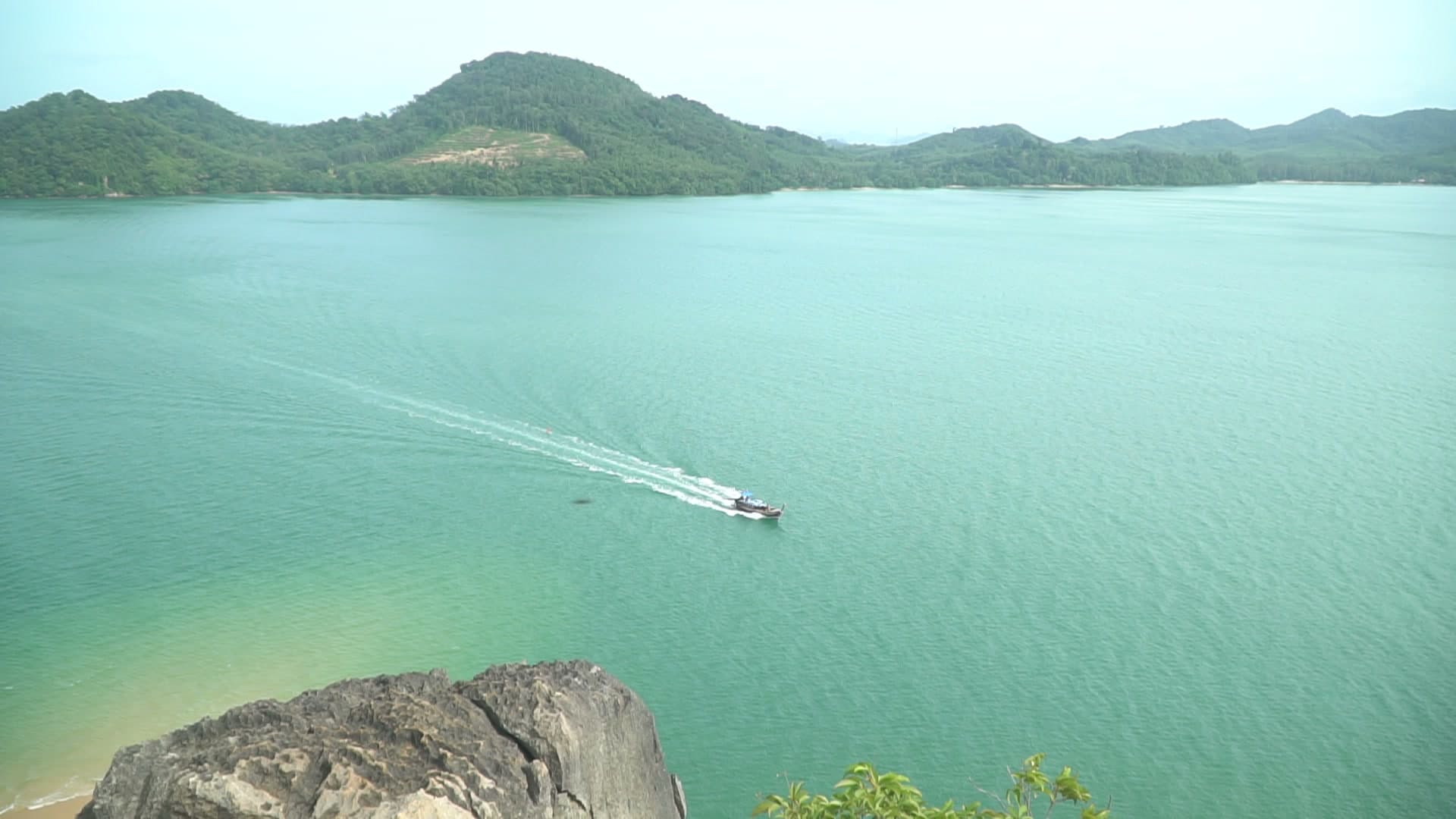 Private longtail boat cruising between tropical islands