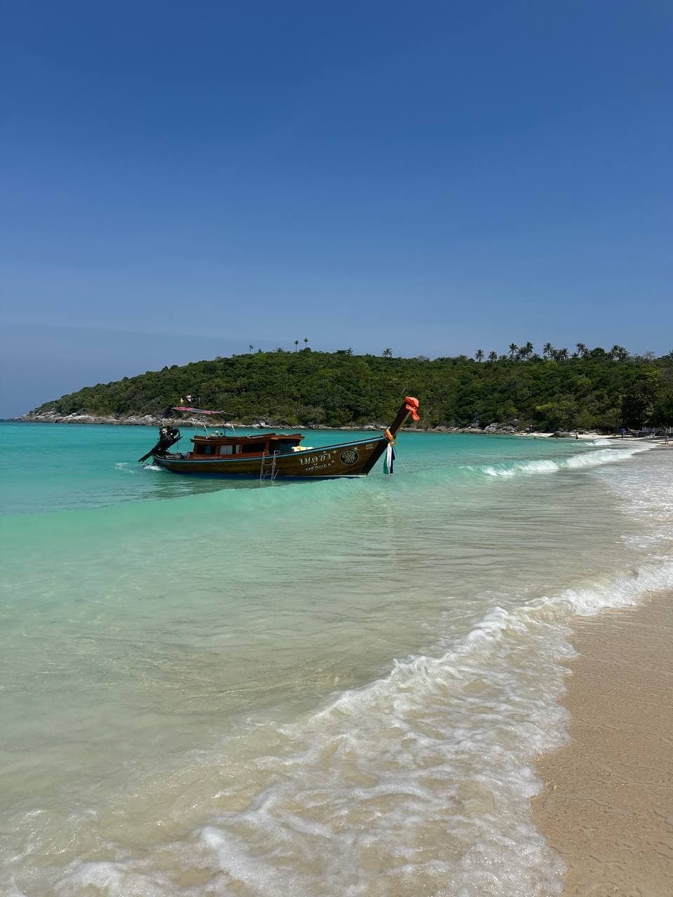 Private longtail boat arriving at a bright island beach